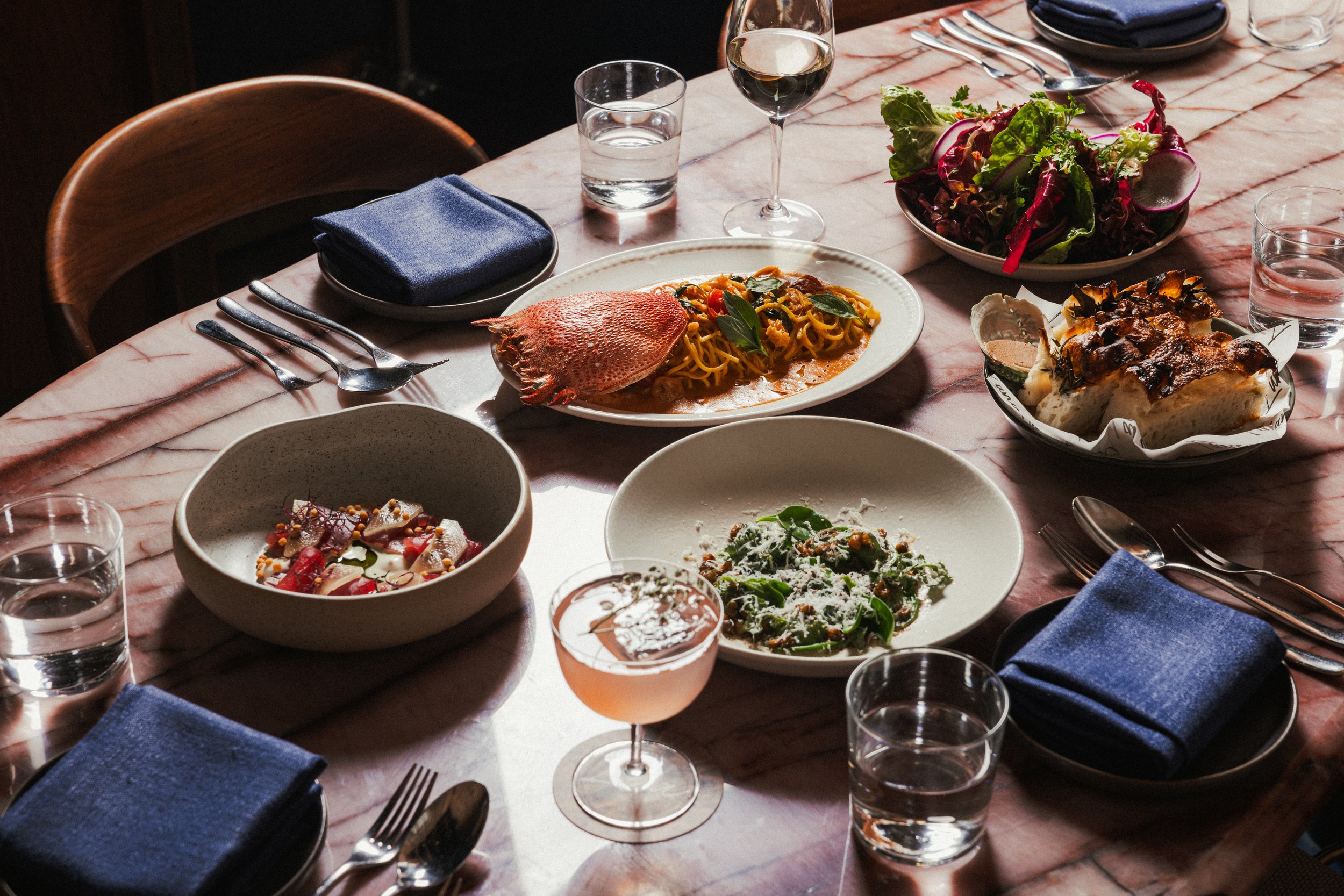 Table with multiple dishes and drinks at Lana